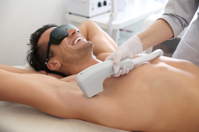 Photo of Young man undergoing laser epilation procedure in beauty salon