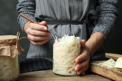 Photo of Woman with fermented cabbage at wooden table, closeup