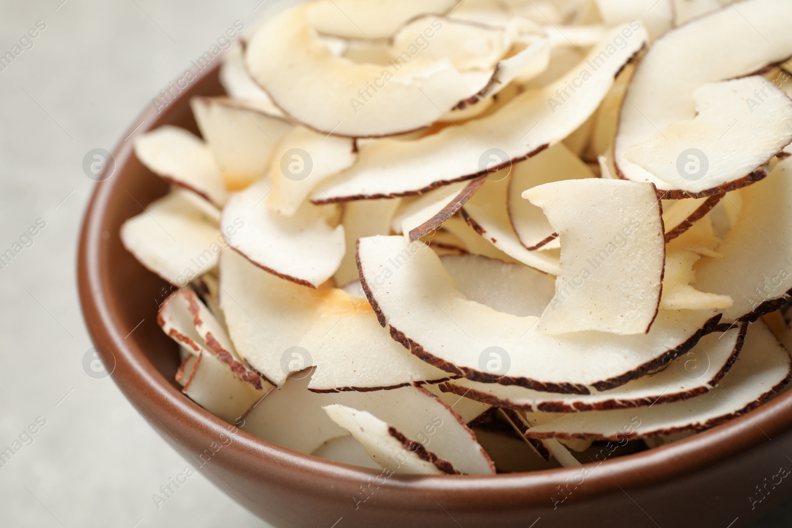 Photo of Tasty coconut chips in ceramic bowl, closeup