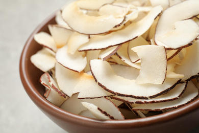 Tasty coconut chips in ceramic bowl, closeup