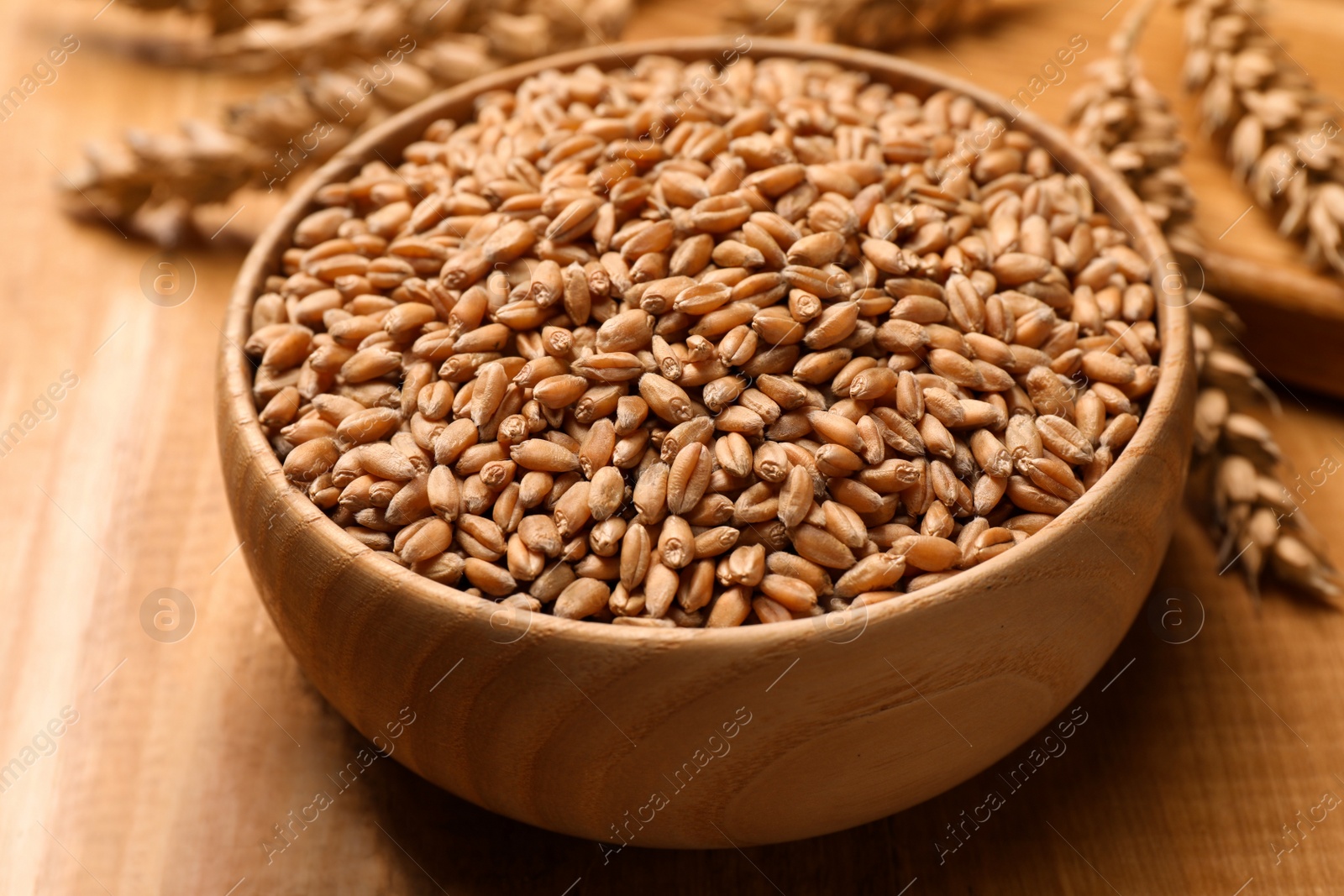 Photo of Wheat grains with spikelets on wooden table, closeup