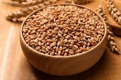 Photo of Wheat grains with spikelets on wooden table, closeup