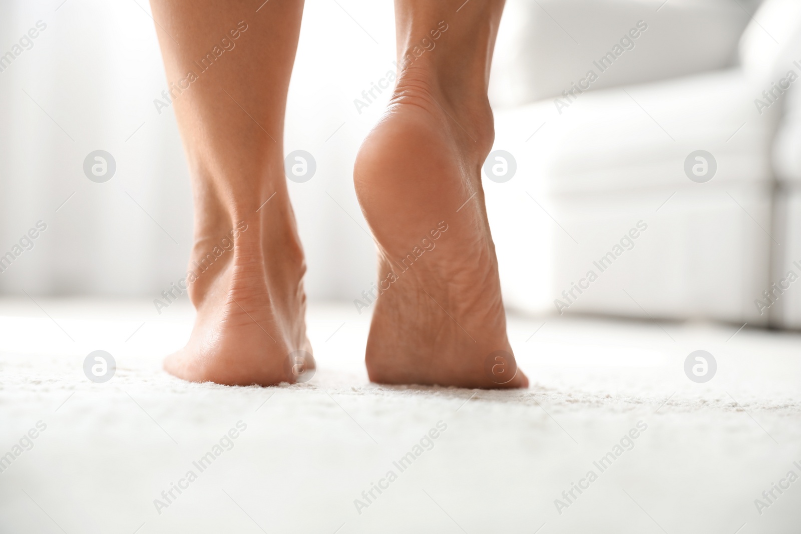 Photo of Young woman suffering from pain in foot indoors, closeup