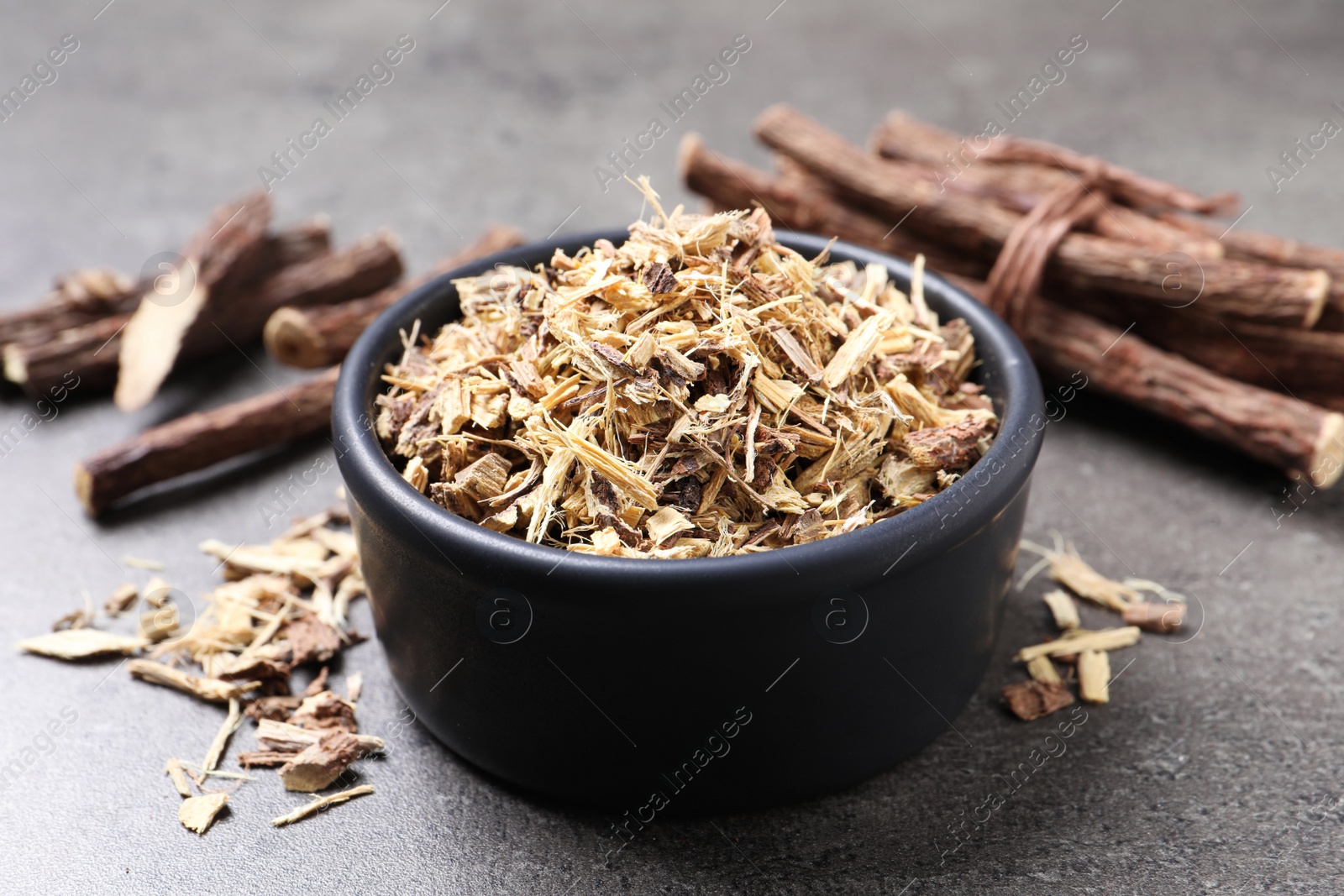 Photo of Dried sticks of liquorice root and shavings on grey table