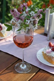 Photo of Glass of rose wine on table served for romantic date in garden