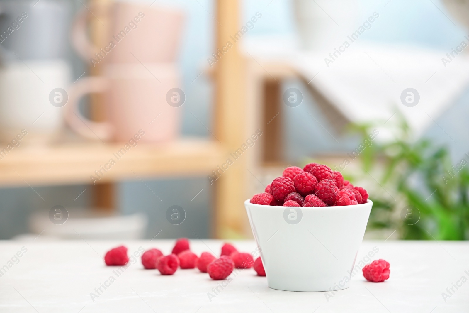 Photo of Bowl with ripe aromatic raspberries on table