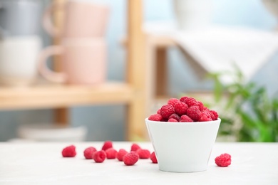 Photo of Bowl with ripe aromatic raspberries on table