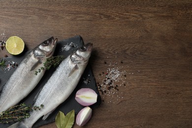 Photo of Sea bass fish and ingredients on wooden table, flat lay. Space for text