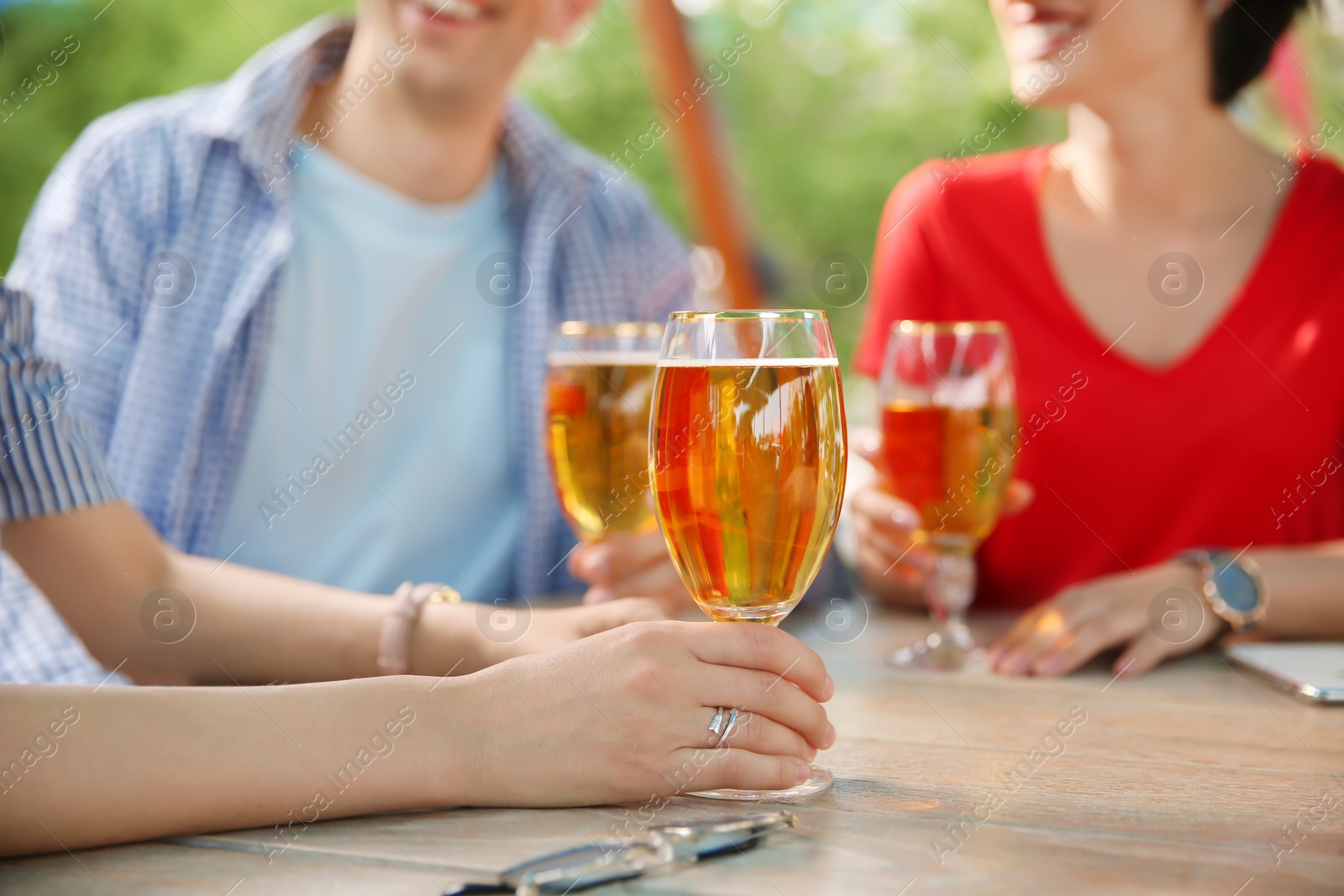 Photo of Young people with glasses of cold beer at table