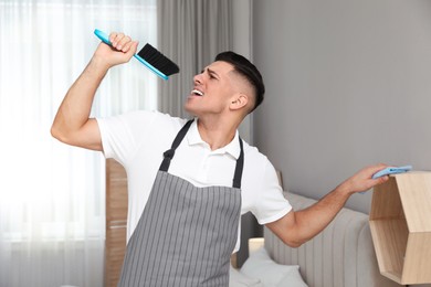 Photo of Man with brush and rag singing while cleaning at home