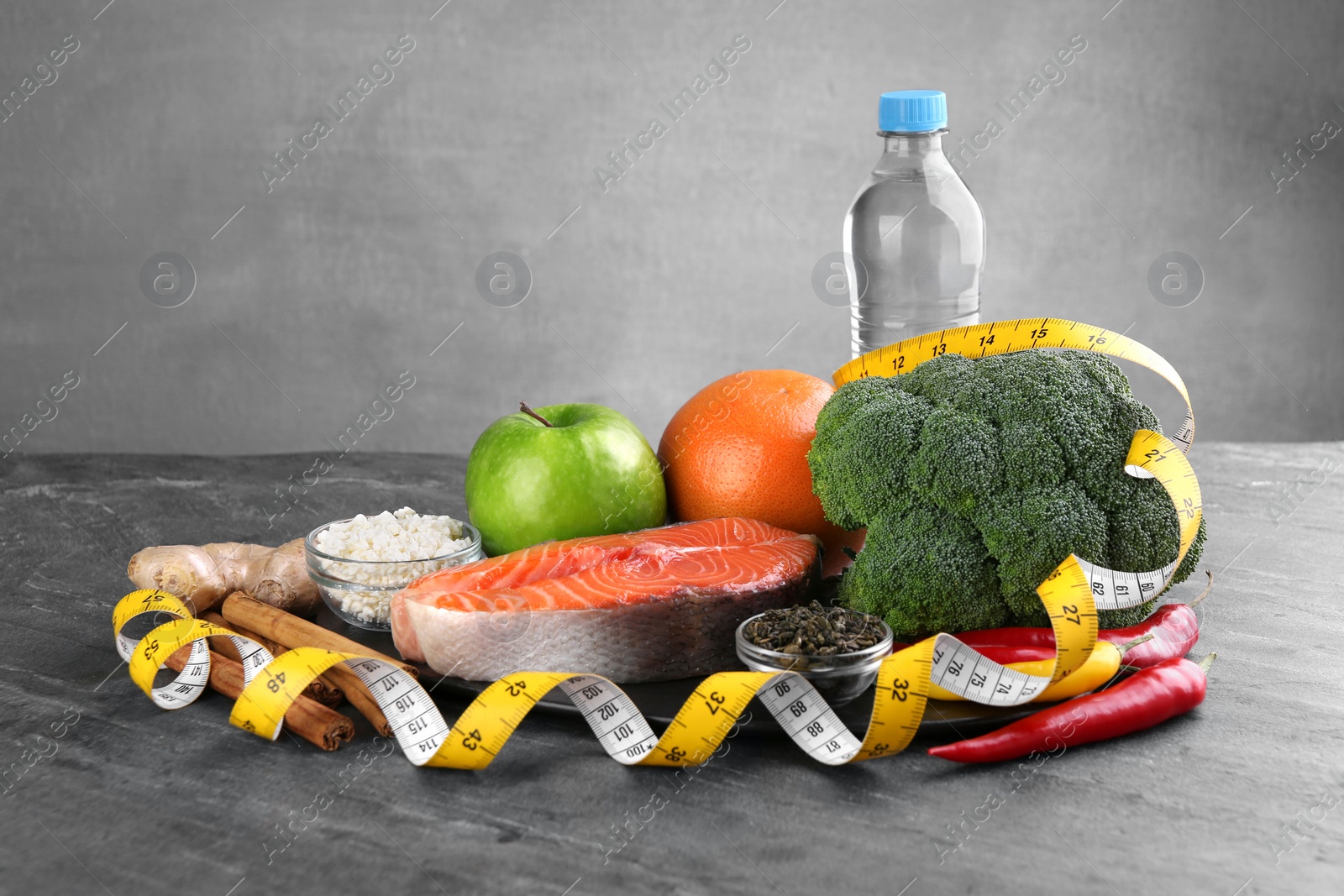 Photo of Metabolism. Different food products and measuring tape on grey table, space for text