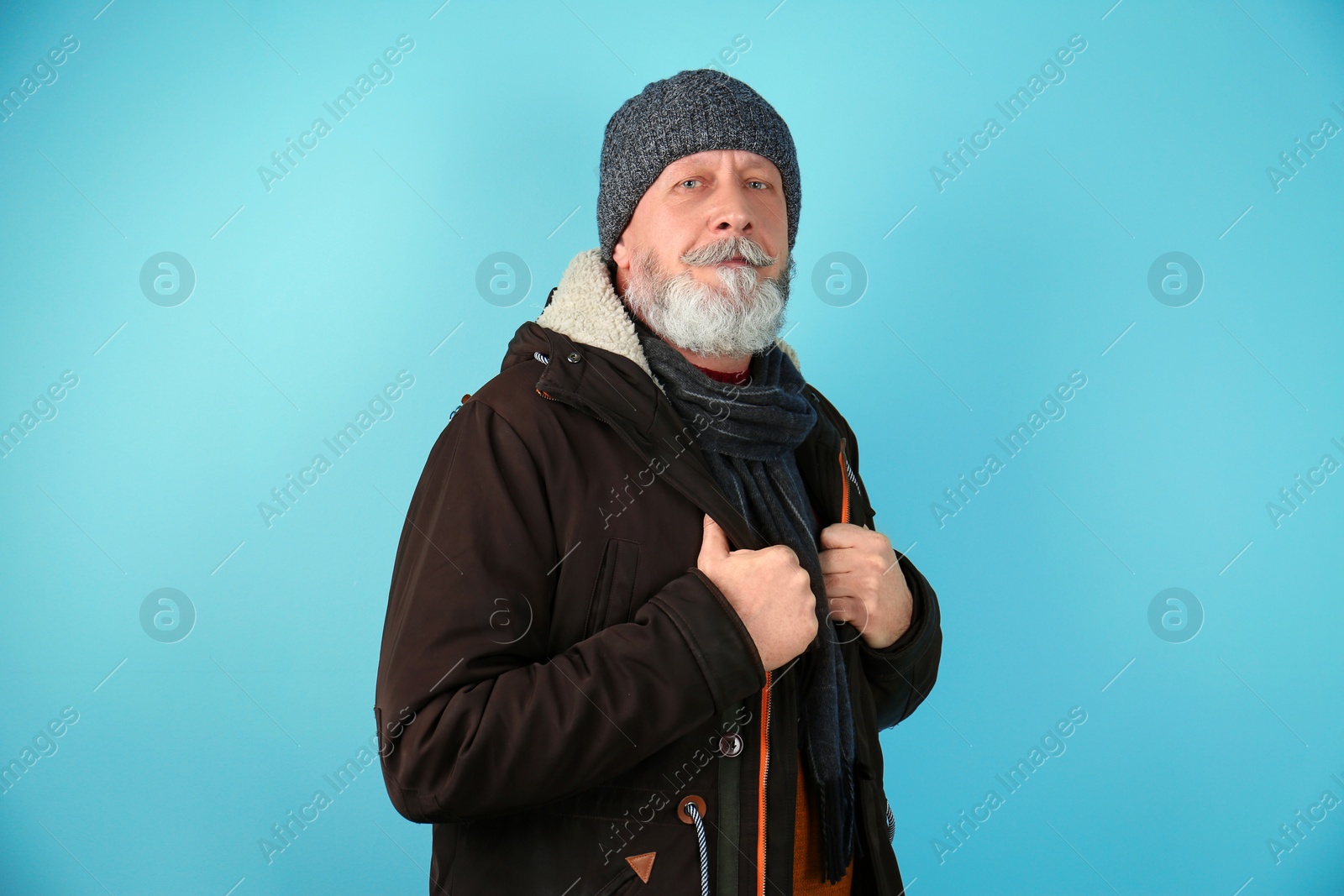 Photo of Mature man in warm clothing on color background. Ready for winter vacation