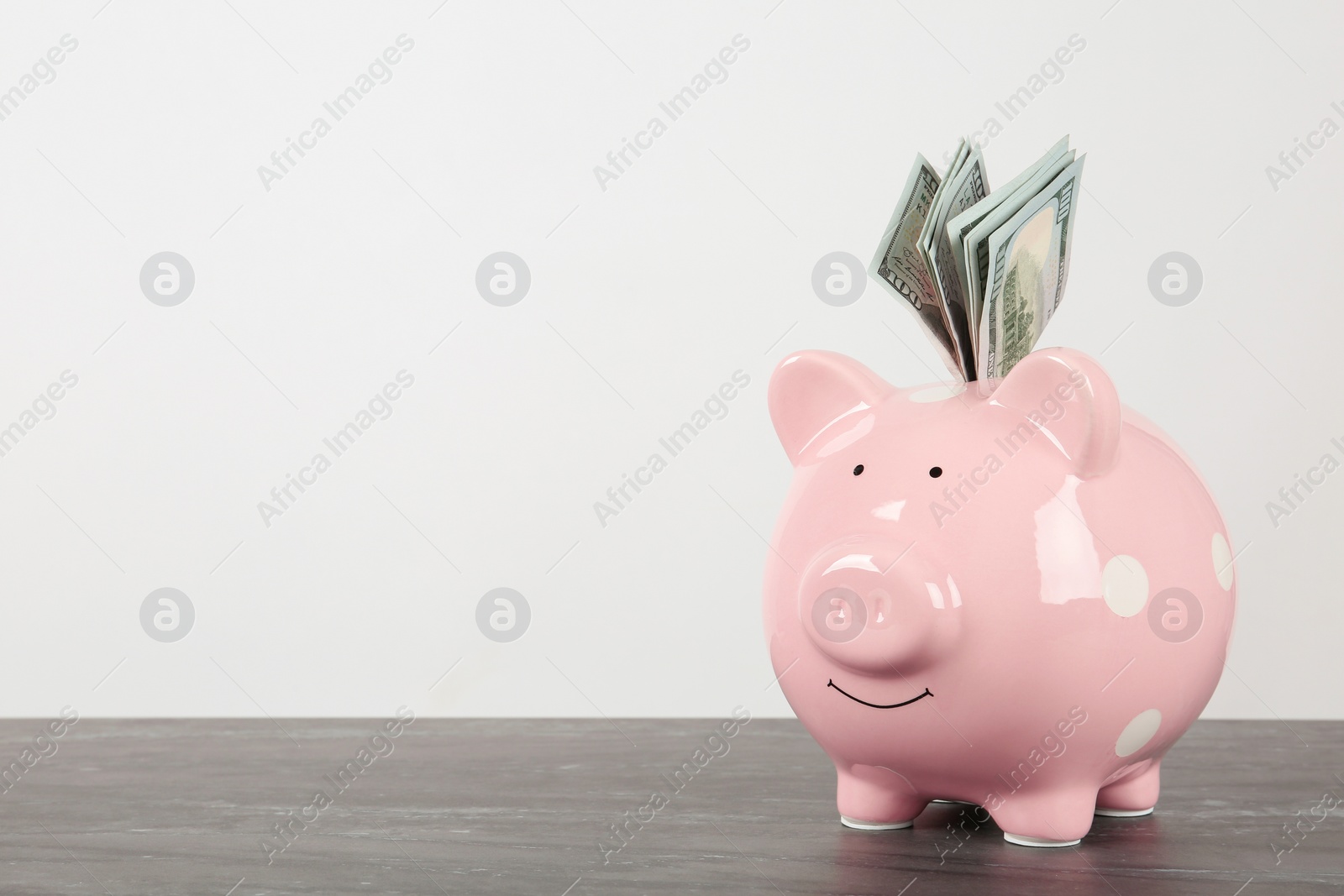 Photo of Piggy bank with dollar banknotes on table against white background. Space for text