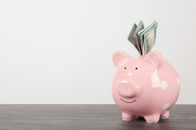 Piggy bank with dollar banknotes on table against white background. Space for text