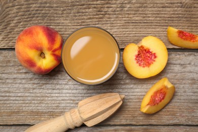 Photo of Glass of peach juice, fresh fruits and citrus reamer on wooden table, flat lay