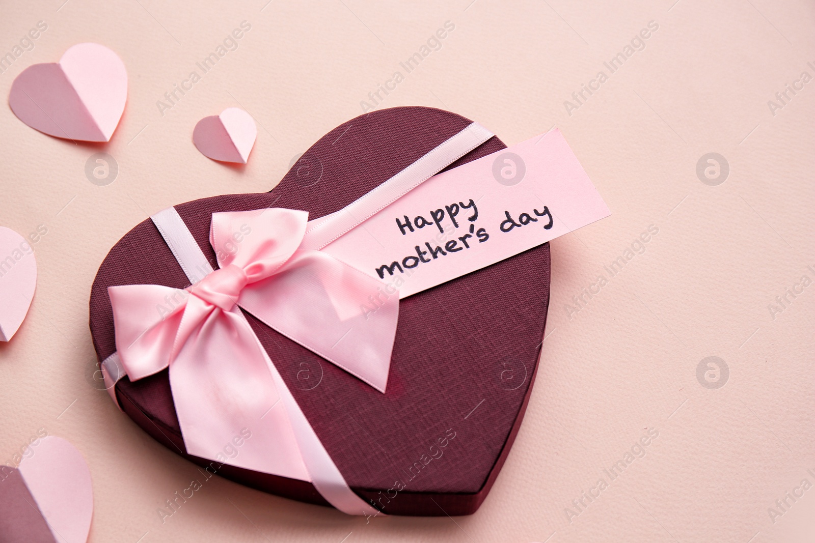 Photo of Gift box, paper hearts and greeting card with text "HAPPY MOTHER'S DAY" on color background