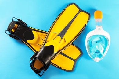 Photo of Pair of yellow flippers and diving mask on color background, top view