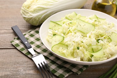 Photo of Tasty salad with Chinese cabbage, cucumber and green onion in bowl on wooden table, closeup