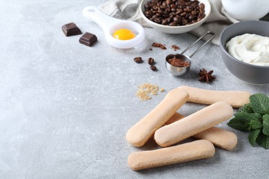 Photo of Tasty cookies and other tiramisu ingredients on grey table, space for text