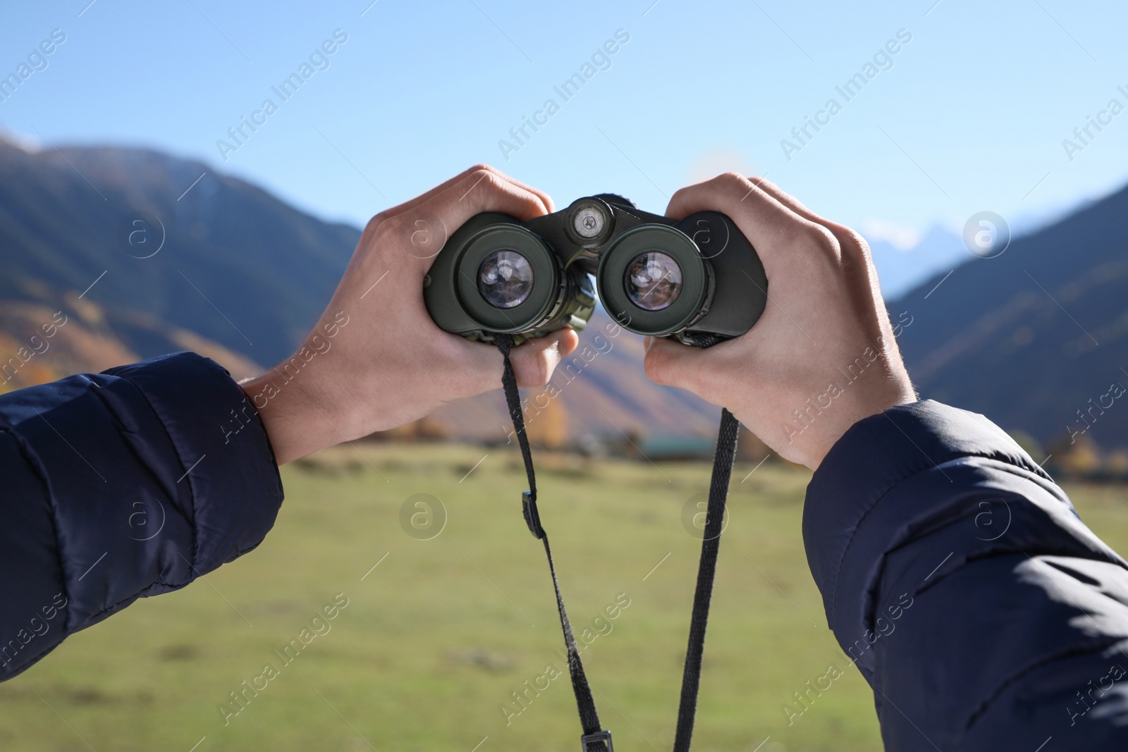 Photo of Boy holding binoculars in beautiful mountains on sunny day, closeup