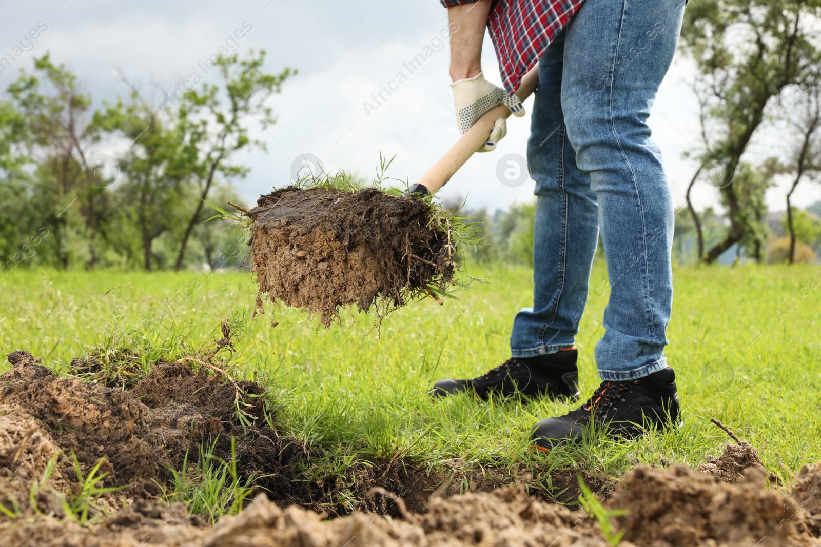 Photo of Worker digging soil with shovel outdoors, closeup