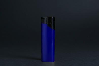 Stylish small pocket lighter on wooden table against black background