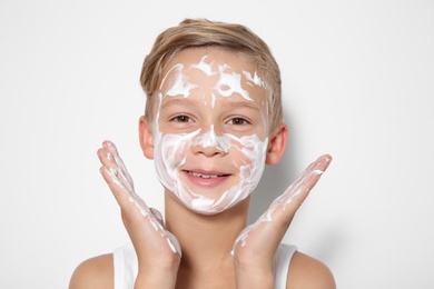 Photo of Cute little boy with soap foam on face against white background