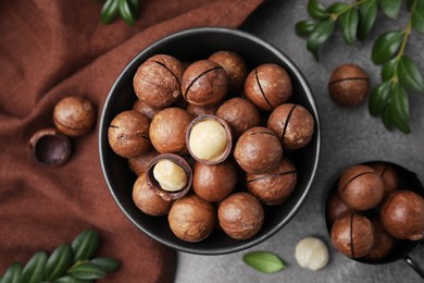 Tasty Macadamia nuts and green twigs on brown table, flat lay