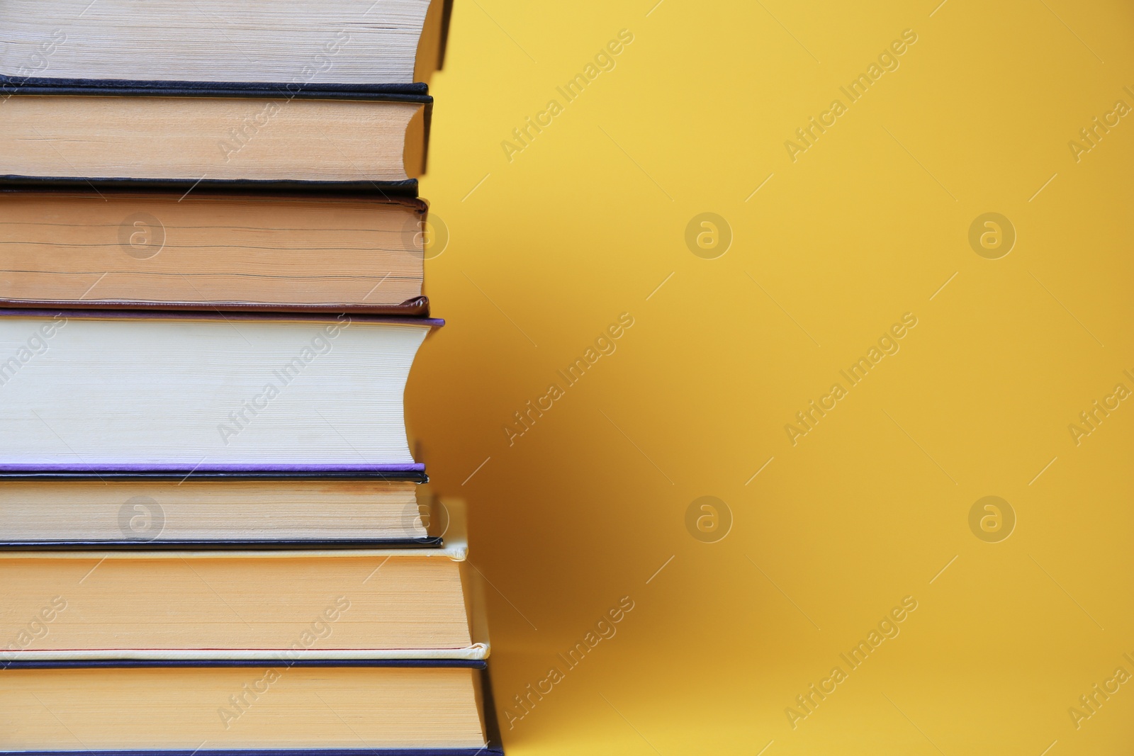 Photo of Collection of hardcover books on yellow background, space for text