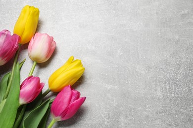 Photo of Beautiful colorful tulip flowers on grey table. Space for text