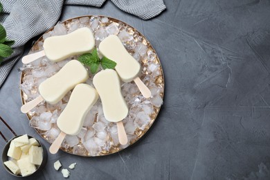 Photo of Flat lay composition with glazed ice cream bars, fresh mint and chocolate on grey table. Space for text