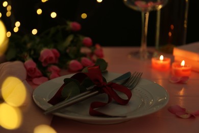 Photo of Place setting with roses and candles on pink wooden table, closeup. Romantic dinner