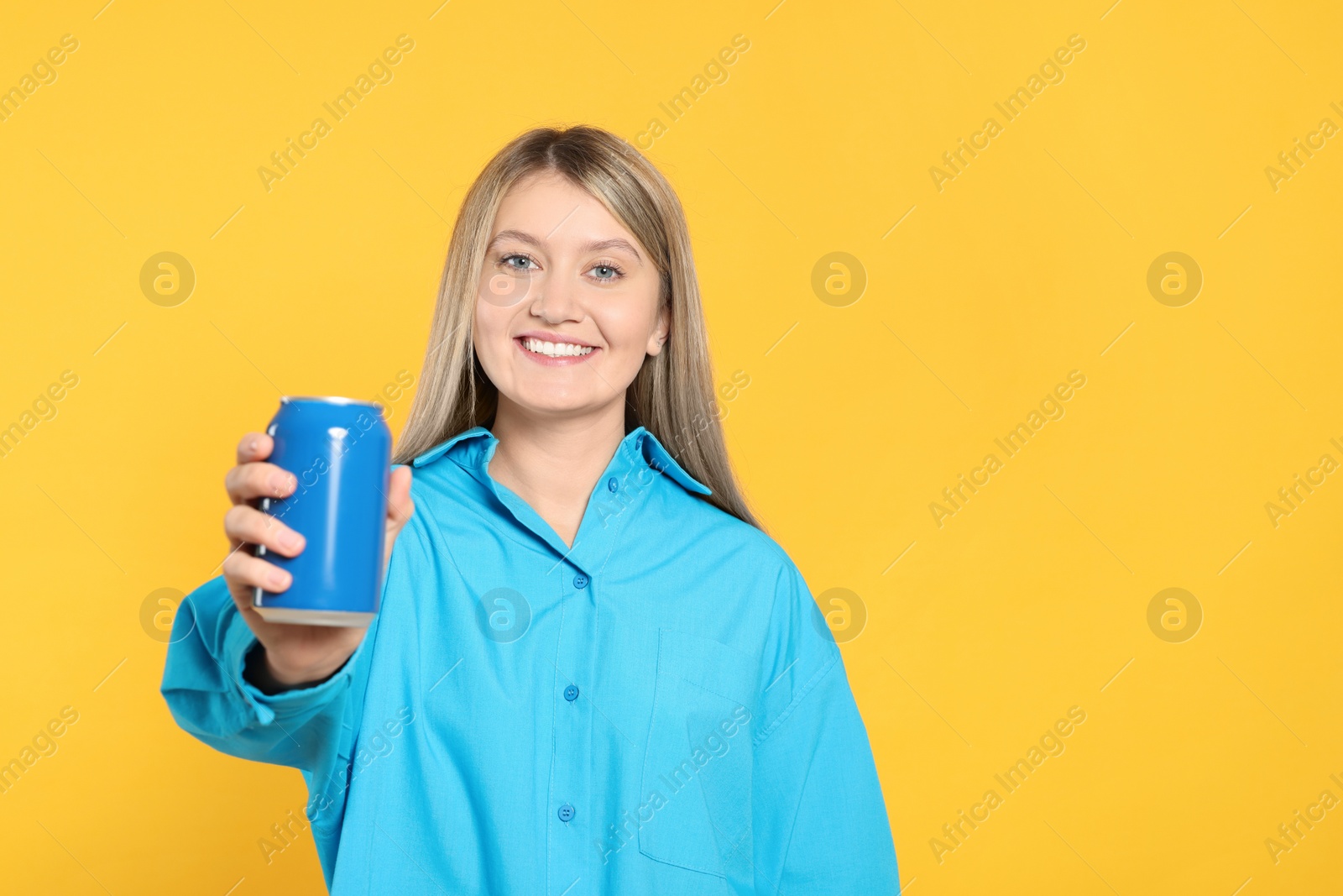 Photo of Beautiful happy woman holding beverage can on yellow background. Space for text