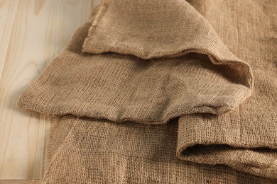 Natural burlap fabric on wooden table, closeup