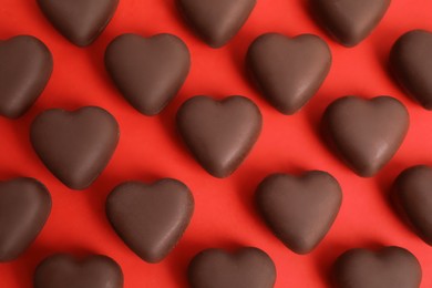Tasty heart shaped chocolate candies on red background, flat lay. Happy Valentine's day