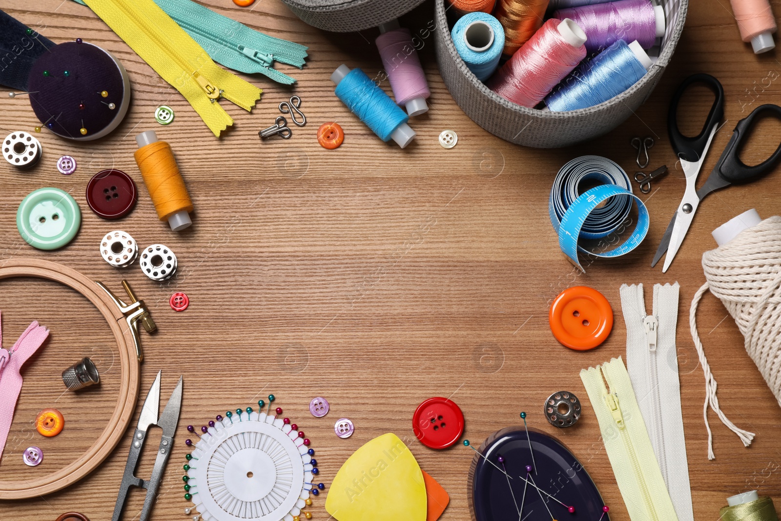 Photo of Frame of different sewing accessories on wooden background, flat lay. Space for text