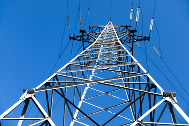 Photo of Modern high voltage tower against blue sky, low angle view