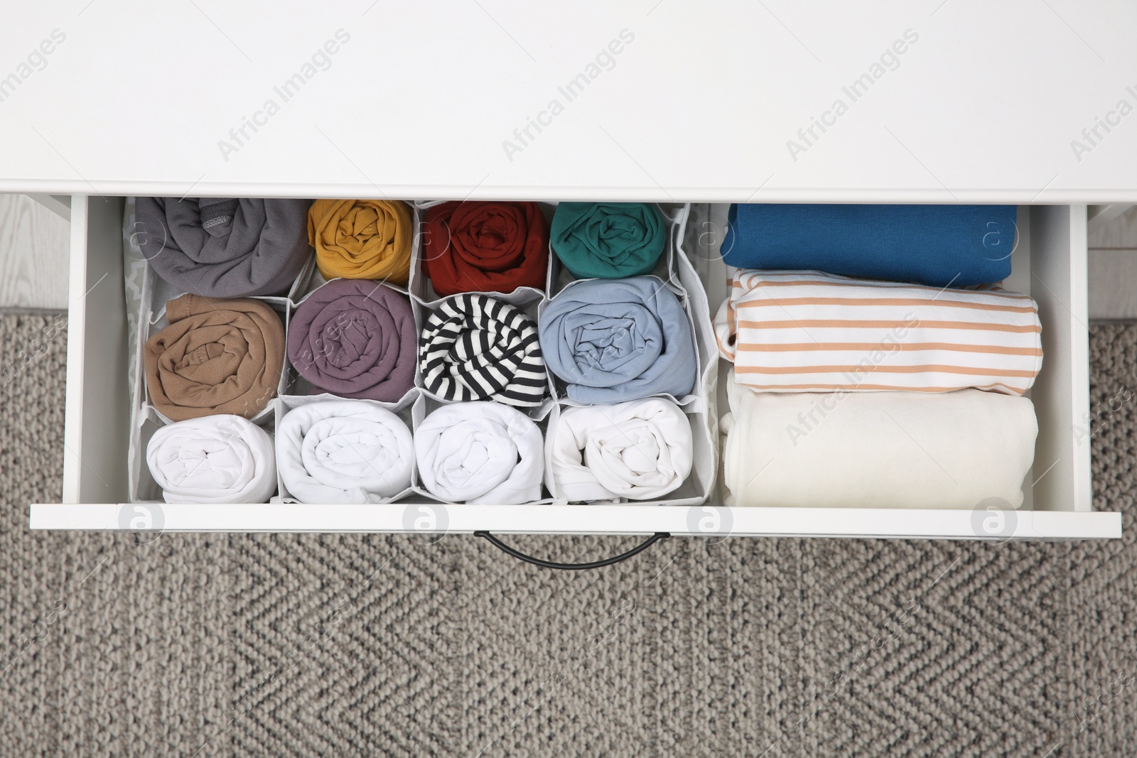 Photo of Open drawer with folded clothes indoors, top view. Vertical storage