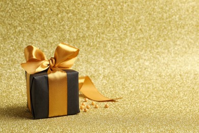 Beautifully wrapped gift box and decor on golden background, space for text