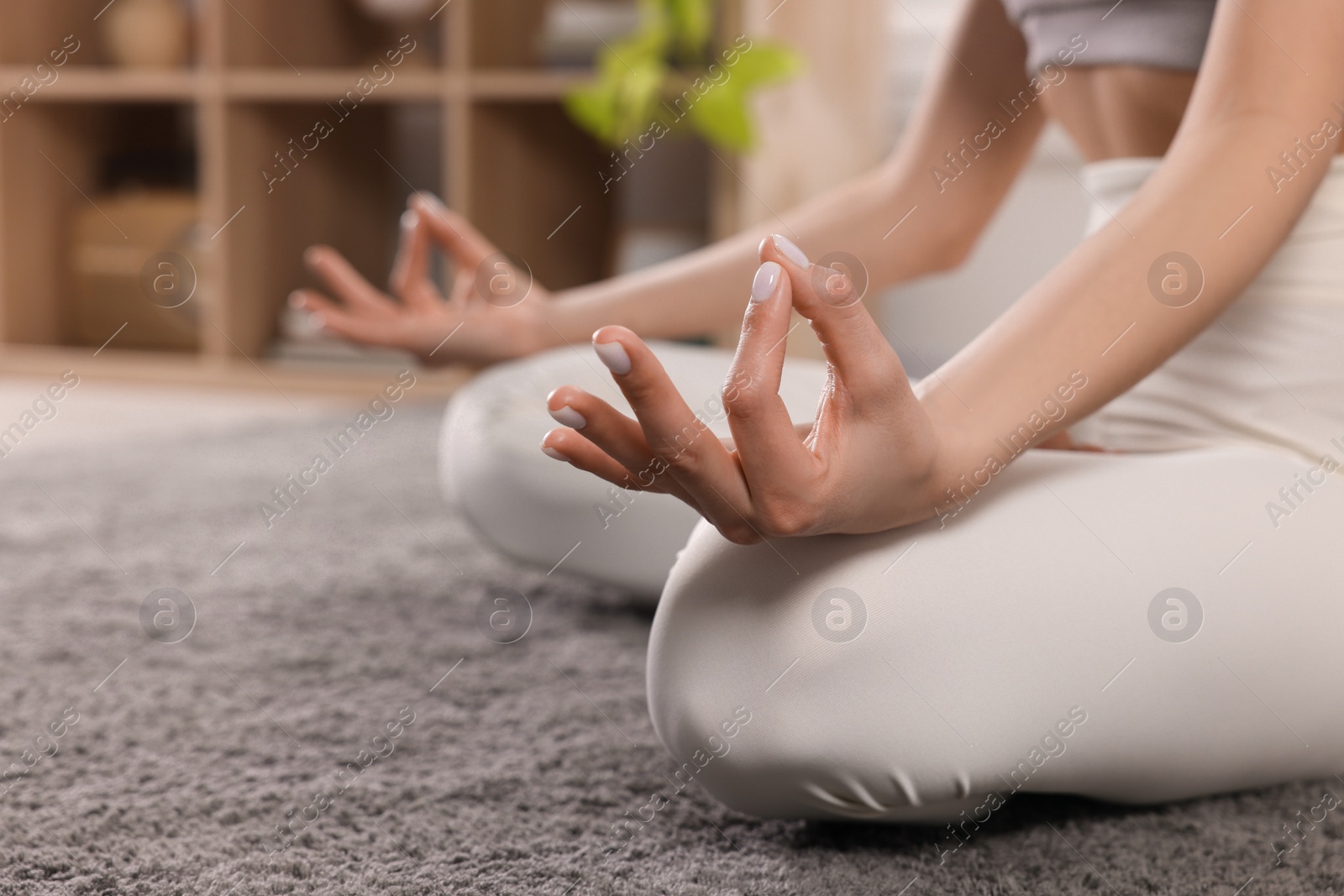 Photo of Woman in sportswear meditating indoors, closeup. Space for text