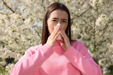 Woman with napkin suffering from seasonal allergy on spring day