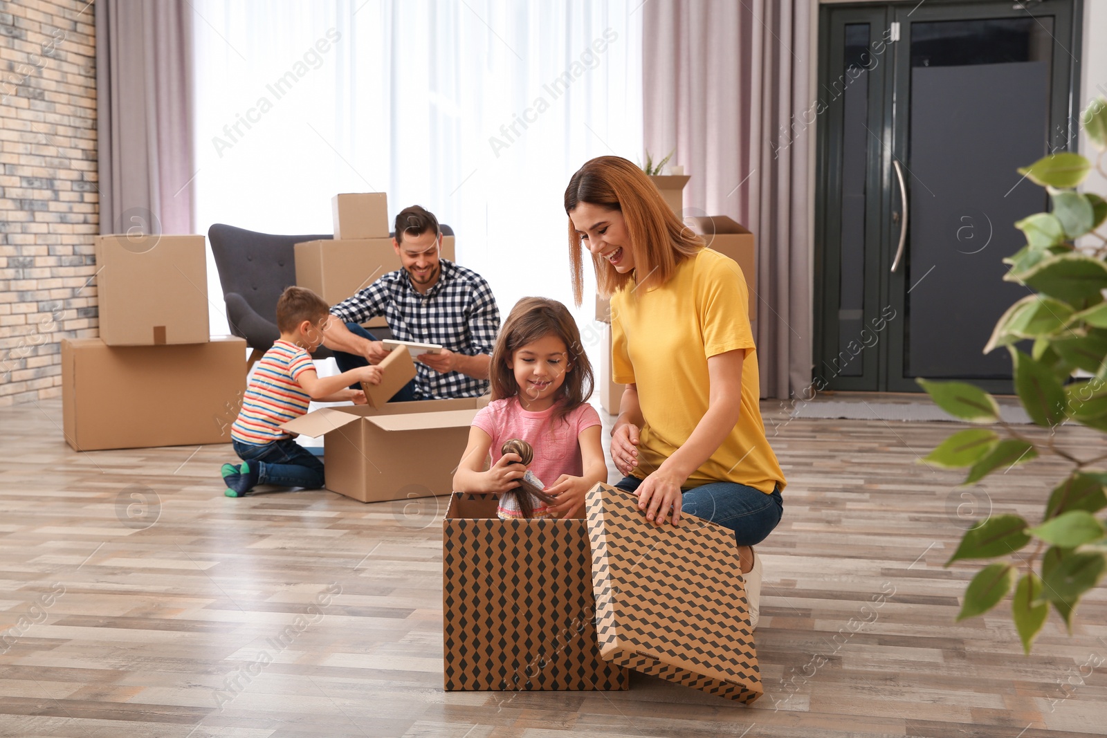 Photo of Family unpacking cardboard boxes in their new house. Moving day