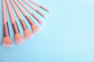 Photo of Flat lay composition with set of professional makeup brushes on light blue background. Space for text