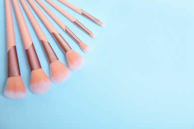 Flat lay composition with set of professional makeup brushes on light blue background. Space for text