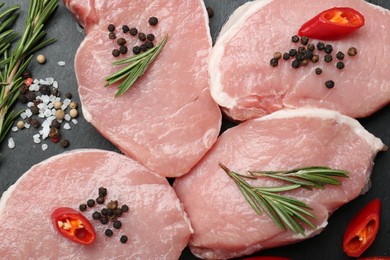 Photo of Pieces of raw pork meat, chili pepper and spices on board, closeup