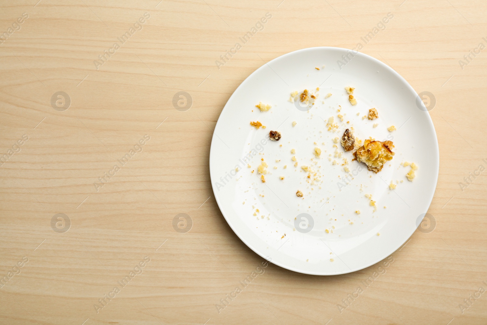 Photo of Dirty plate with food leftovers on wooden background, top view. Space for text