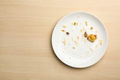 Dirty plate with food leftovers on wooden background, top view. Space for text