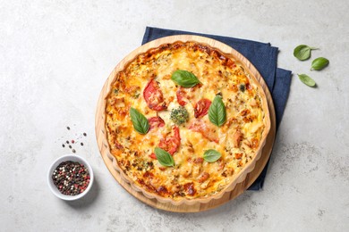 Photo of Tasty quiche with cheese, tomatoes and basil leaves on light grey table, flat lay