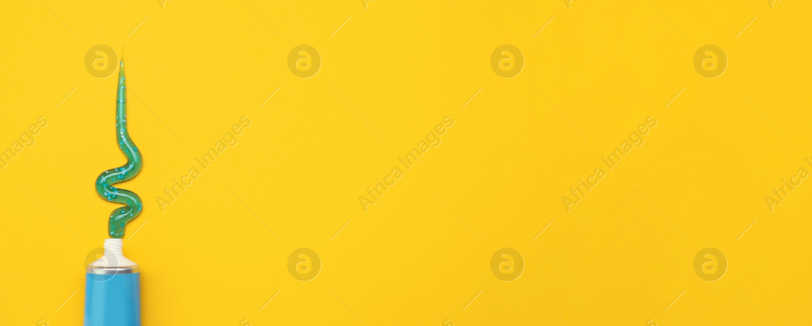 Image of Tube with squeezed out toothpaste on yellow background, top view with space for text. Banner design