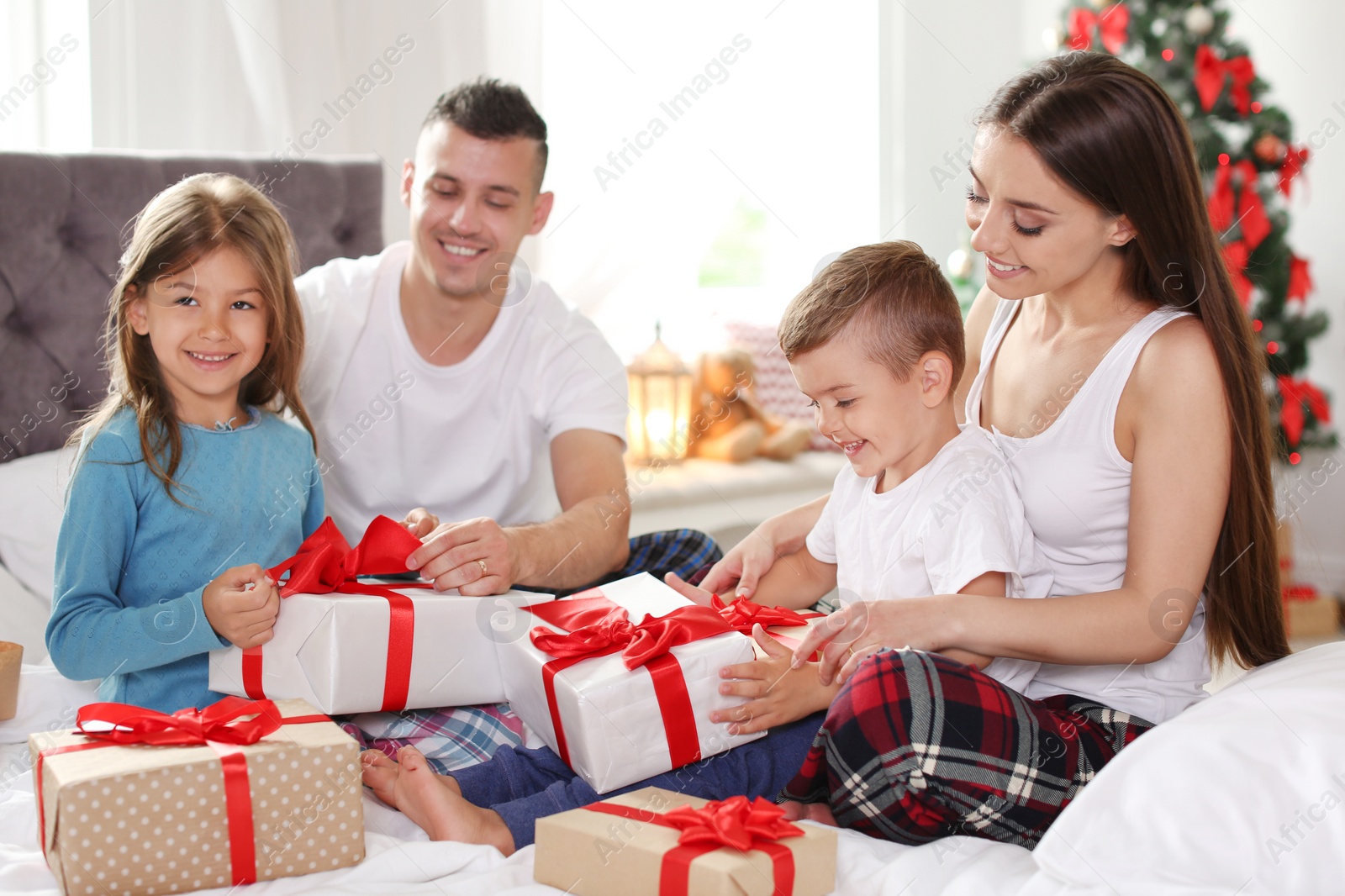 Photo of Happy parents and children exchanging gifts on Christmas morning at home